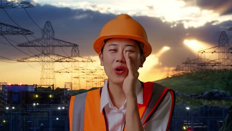 close up of asian female engineer with safety helmet yelling with hand over mouth while standing near high voltage tower