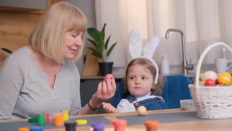 Grandmother and granddaughter paint Easter eggs. Easter holiday concept. The family rests together