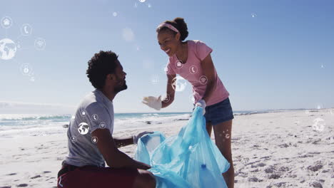 animación de iconos del globo sobre un feliz hombre y mujer afroamericanos recogiendo basura de la playa
