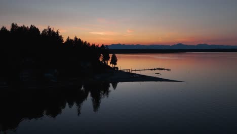 drone shot rotating around herron island at sunset to reveal the cascade mountains