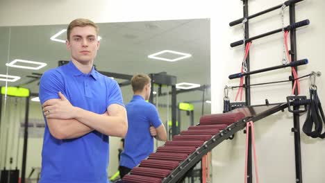 a man in an electric blue tshirt confidently prepares to work out in the gym an individual wearing a blue tshirt is seen in an indoor gym standing confidently next to a machine with arms crossed with an electric blue shirt he exudes determination for his workout session
