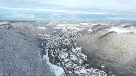 Amazing-aerial-flying-towards-snow-covered-village-Honau-and-forest-with-blue-sky-during-winter-in-Swabia,-Germany