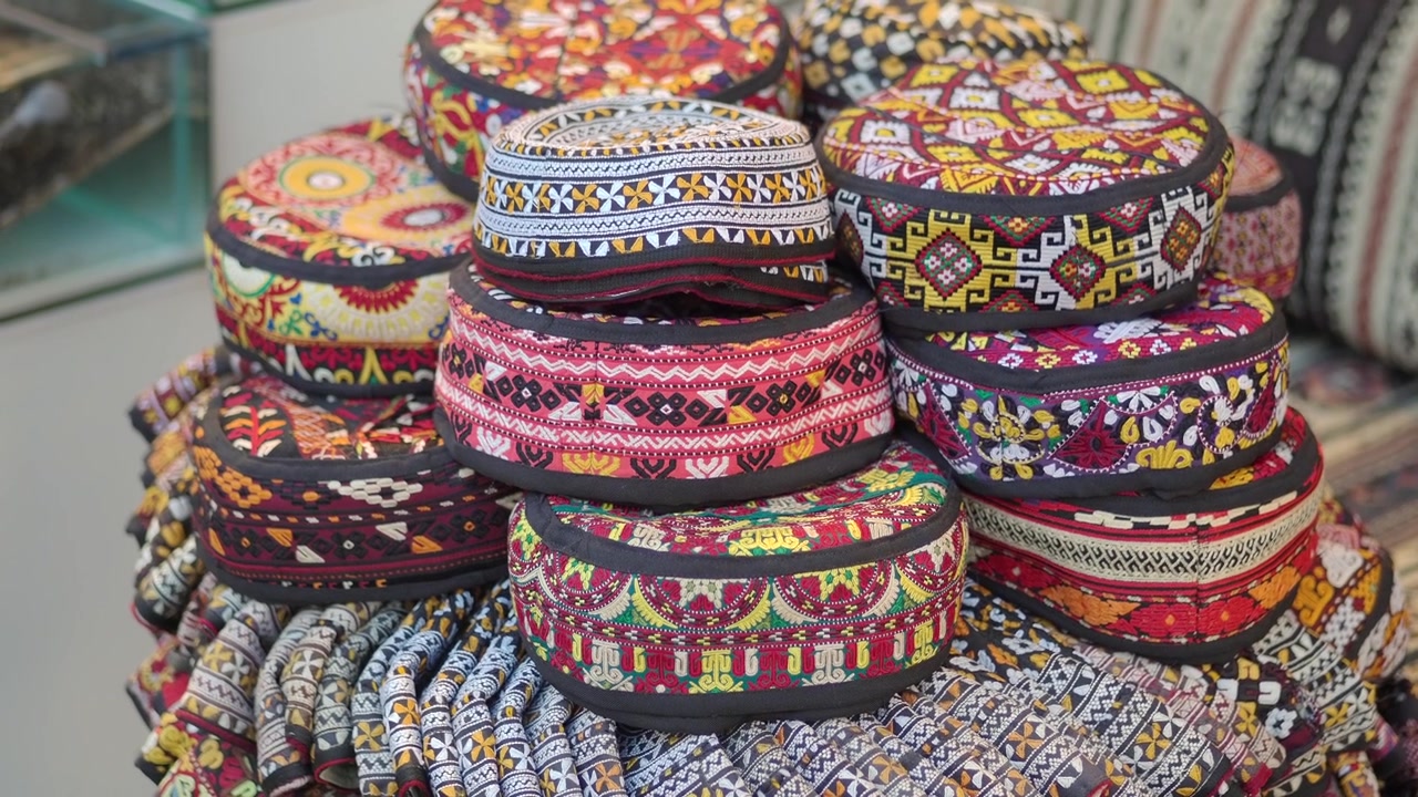 Pila di cappelli tradizionali ricamati in un mercato.