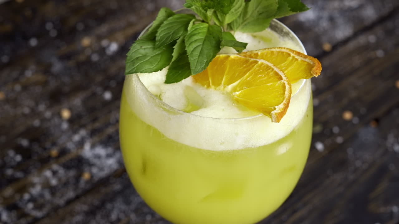 Et glas gul lemonade med mynte på en træoverflade