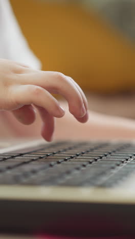 little boy types message on laptop sitting at desk. preschooler presses keys with finger. toddler learns computer keyboard closeup on blurred background