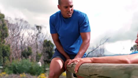 couple climbing over the hurdle during obstacle course