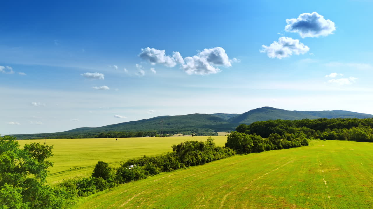 Scenic countryside landscape in Europe. Lush green fields stretch under a bright blue sky with fluffy clouds in this picturesque European countryside