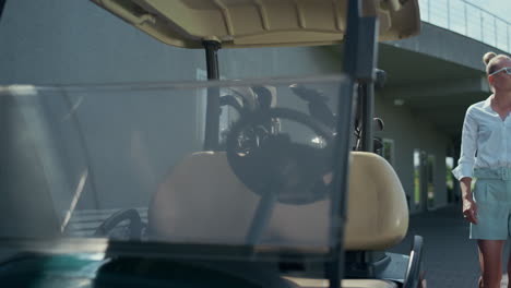 woman sitting golf cart on sunny day. professional player start engine on course