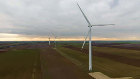 Windkraftanlagen,-Luftaufnahme,-Verfolgung-In-Richtung.-Sonnenuntergang-Frankreich-Erntefelder-Bewölkt