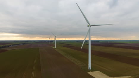 wind turbines aerial shot tracking towards. sunset france crop fields cloudy