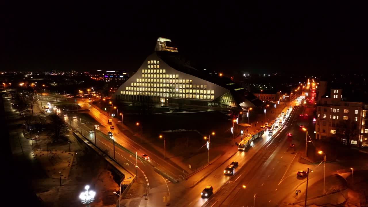 Riga’s iconic National Library standing tall at night, vibrant lights, drone