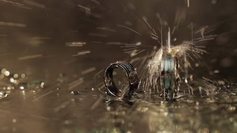 Anillos-De-Boda-En-La-Superficie-Del-Agua-Oscura-Que-Brilla-Con-Luz.-Gotas-De-Agua.-Primer-Plano