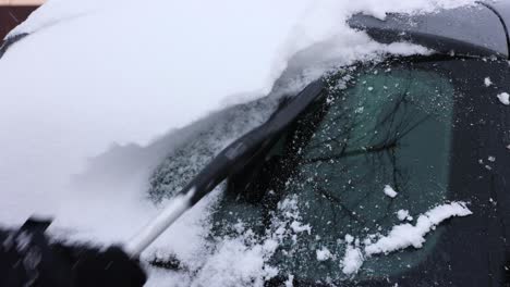 woman hand cleaning snow from the car in winter - close up