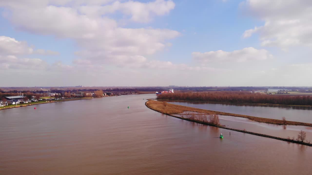 바렌드레흐트 (barendrecht) 의 올데 마스 (oude maas) 를 날아다니며 푸른 하늘과 구름을 볼 수 있으며, 화물선이 멀리서 접근하고 있습니다.