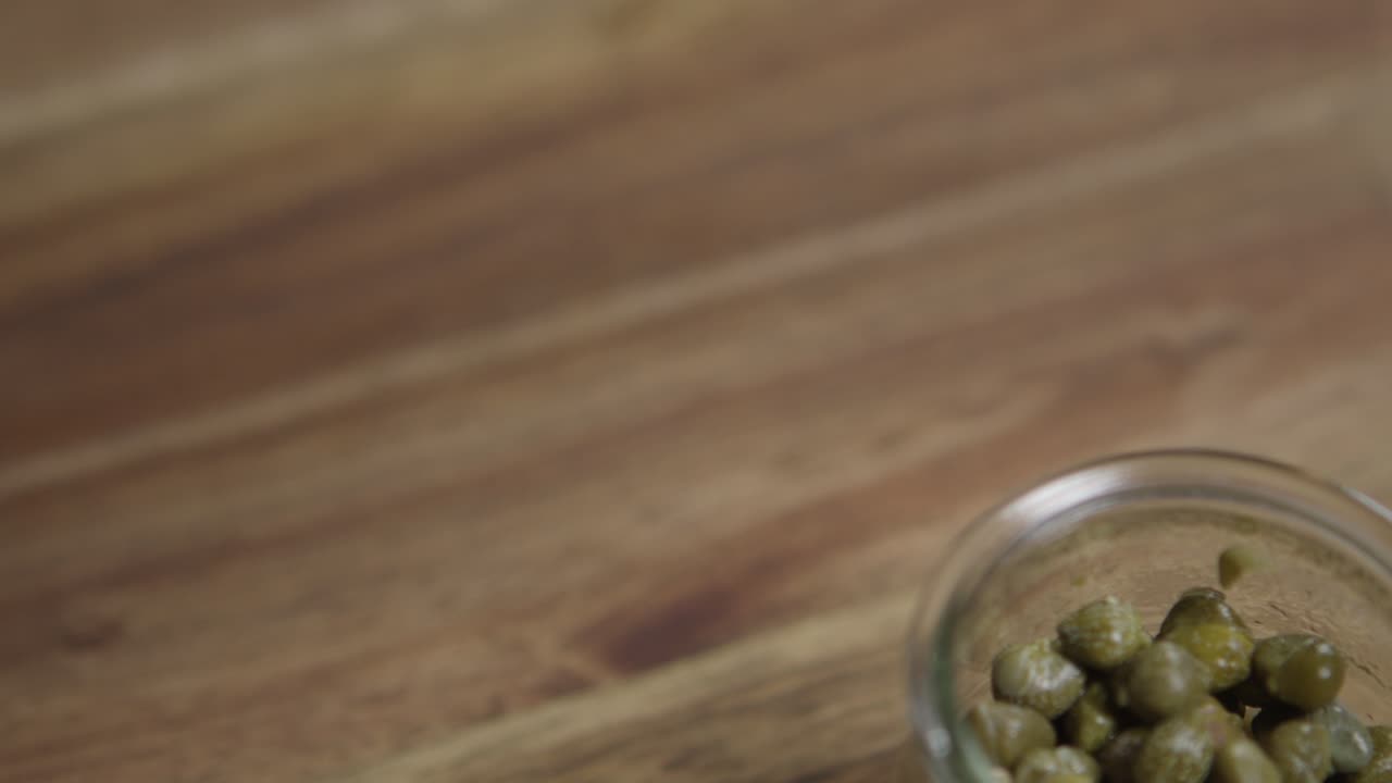 disparo en primer plano de la alcaparra sentada en un pequeño frasco de vidrio