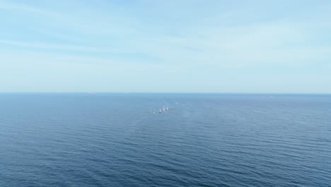 clear peaceful sea and pastel blue sky panorama with sailboats soothing aerial shot