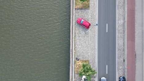 Antena-Aérea-Hacia-Abajo-Del-Canal-Junto-A-La-Carretera-Con-Un-Coche-Rojo-Estacionado,-En-Gante