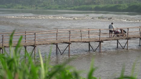 a group of people are maintaining and repairing a bridge made of wood. the bridge connects the villages of bantul and kulonprogo.