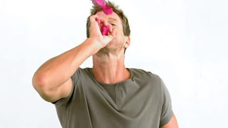 man blowing pink confetti on white background