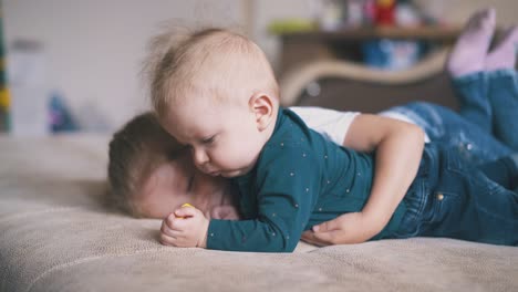 lovely girl hugs brother nibbling yellow circle on bed