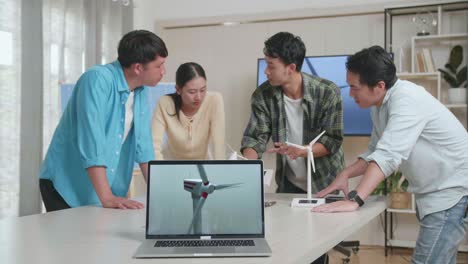테이블 위의 노트북은 아시아 엔지니어 그룹이 사무실에서 작업에 대해 논의하는 동안 풍력 터빈의 비디오를 보여주고 있습니다.