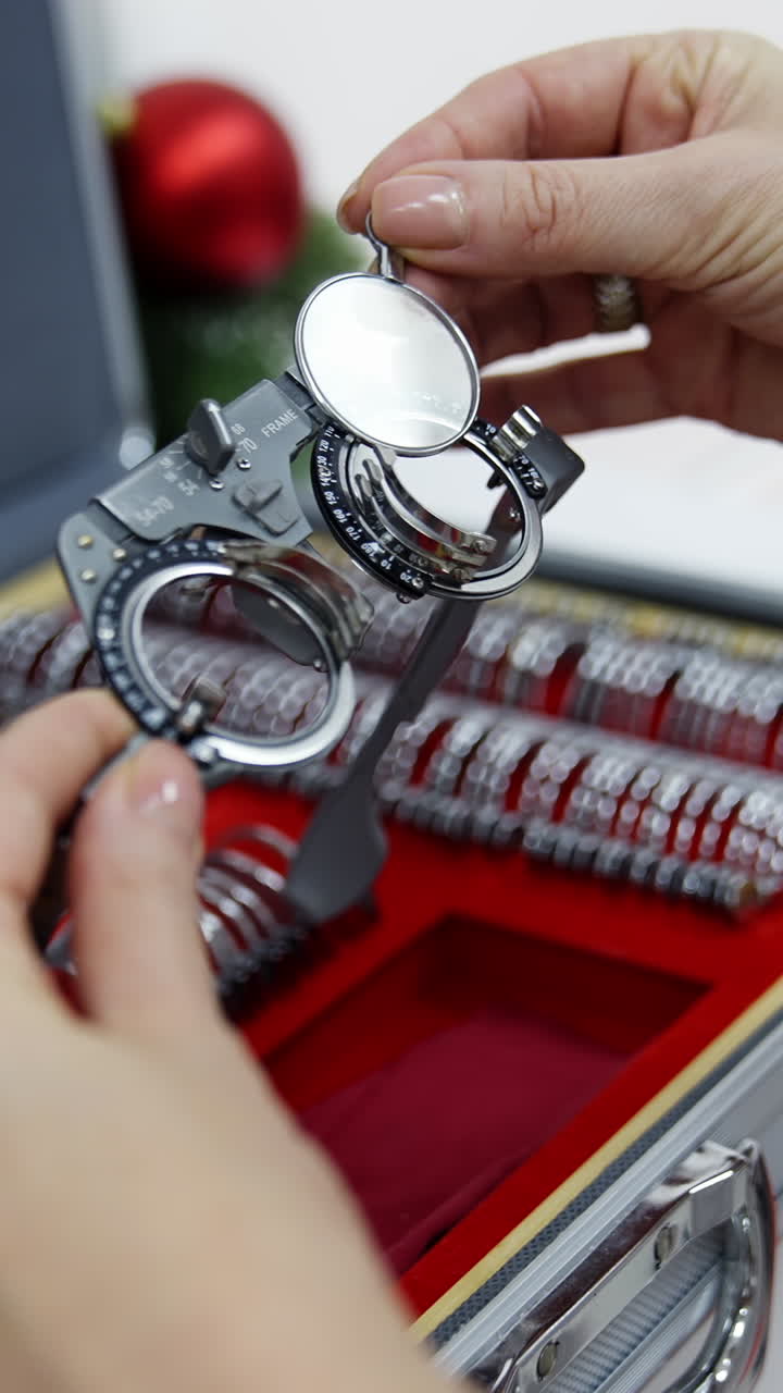 Doctor selecting lenses to the trial frame. Hands of female optometrist picking up test lenses from case for eyesight examination Close-up. Vertical video