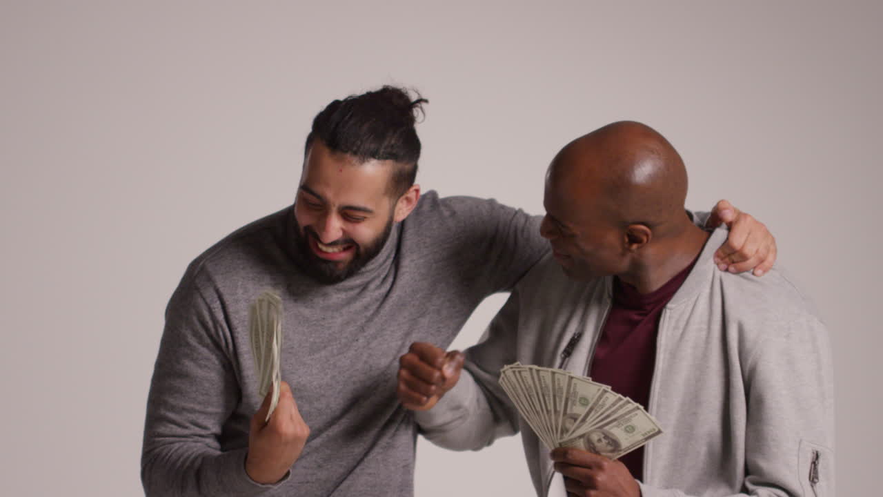Studio Shot Of Two Excited Male Friends Celebrating Winning Cash Prize Throwing Handful Of 100 Dollar Bills In The Air 1