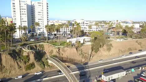 Puente-Peatonal-De-La-Autopista-De-La-Costa-Pacífica-En-El-Centro-De-La-Atrevida-Vista-Aérea-Vuelo-Inclinación-Hacia-Arriba-Imágenes-De-Drones-En-La-Playa-De-Santa-Monica-California-Estados-Unidos-2018