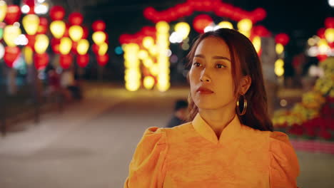 Beautiful-Vietnamese-woman-in-slow-motion-contemplating-and-thinking-while-walking-at-night-with-lanterns,-Hoi-An,-Vietnam