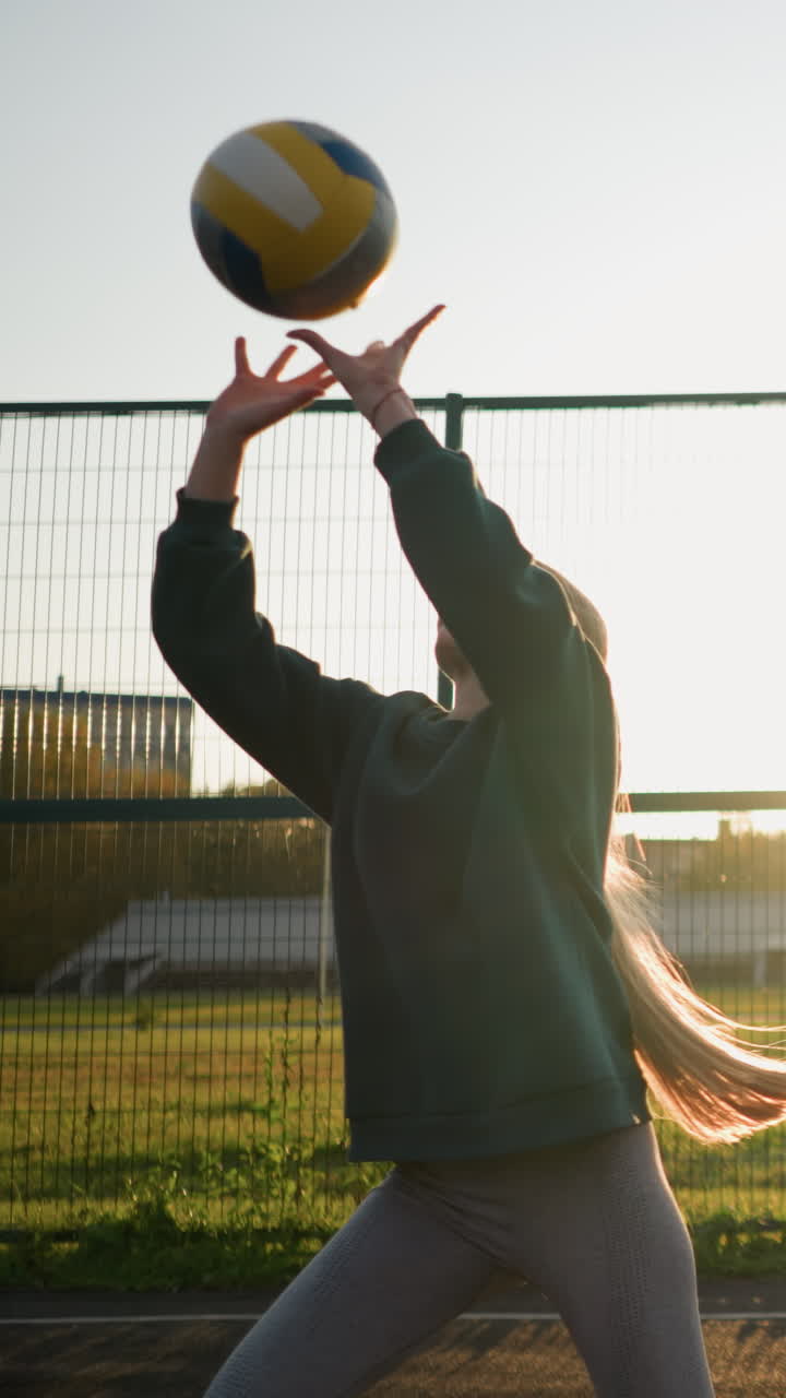 야외에서 볼리볼을 연습하는 초보자, 배경에는 축구장과 빛이 공을 제공하는 연습을 할 때 손 주변에 따뜻한 빛을 만니다.