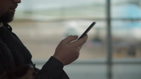 hombre usando un teléfono inteligente en el aeropuerto