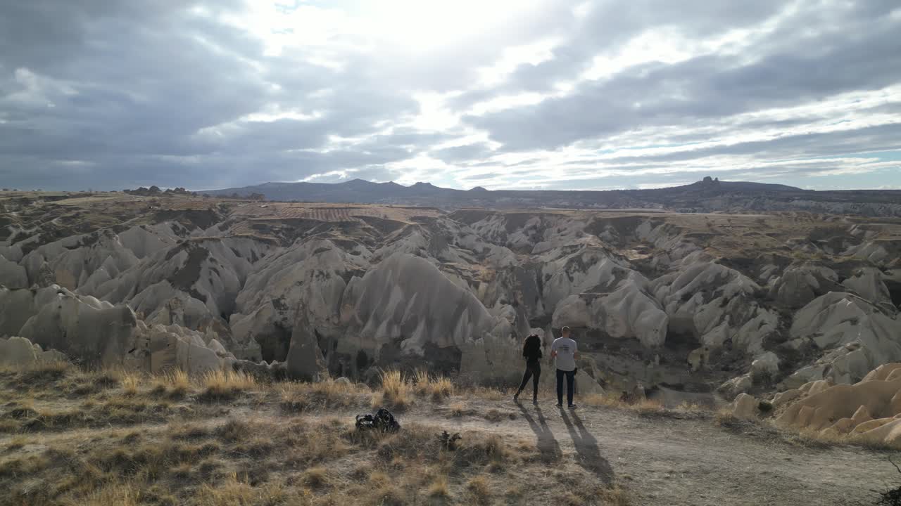пара стоит на краю горы и любуется сказочными дымоходами в каппадокии, турция