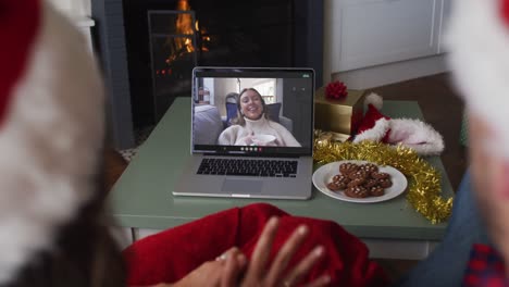 Happy-caucasian-couple-on-video-call-on-laptop-with-female-friend-at-christmas-time