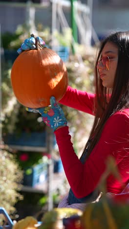 mujer sosteniendo una calabaza en un jardín