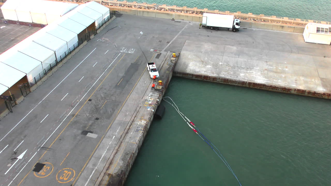Dockworkers secure a ship's ropes at the pier