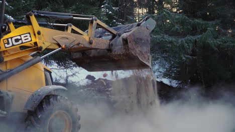 yellow jcb excavator loading dirt in winter forest