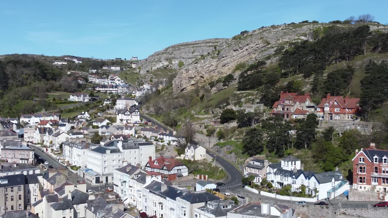 Alberghi colorati della cittadina turistica costiera di Llandudno contro il monte Great Orme, ripresa aerea con panoramica lenta verso destra.