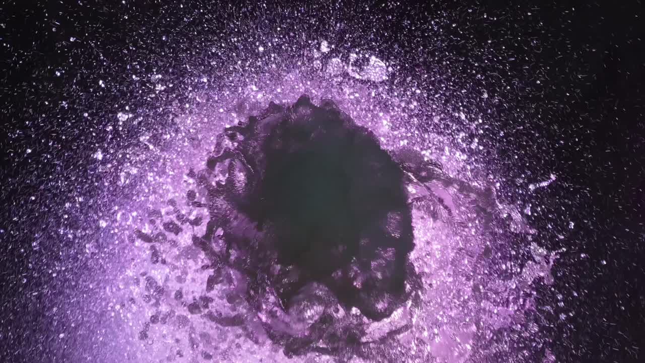 top close shot de la fuente de color púrpura fluyendo, agua salpicando alrededor