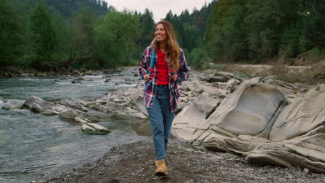 mujer caminando por la orilla del río en el bosque