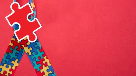 animation of red and yellow puzzle pieces falling over autism awareness ribbon formed with puzzles