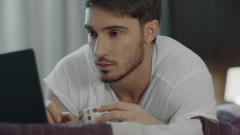 Man-working-laptop-with-coffee-cup-in-bed.-Male-blogger-work-online