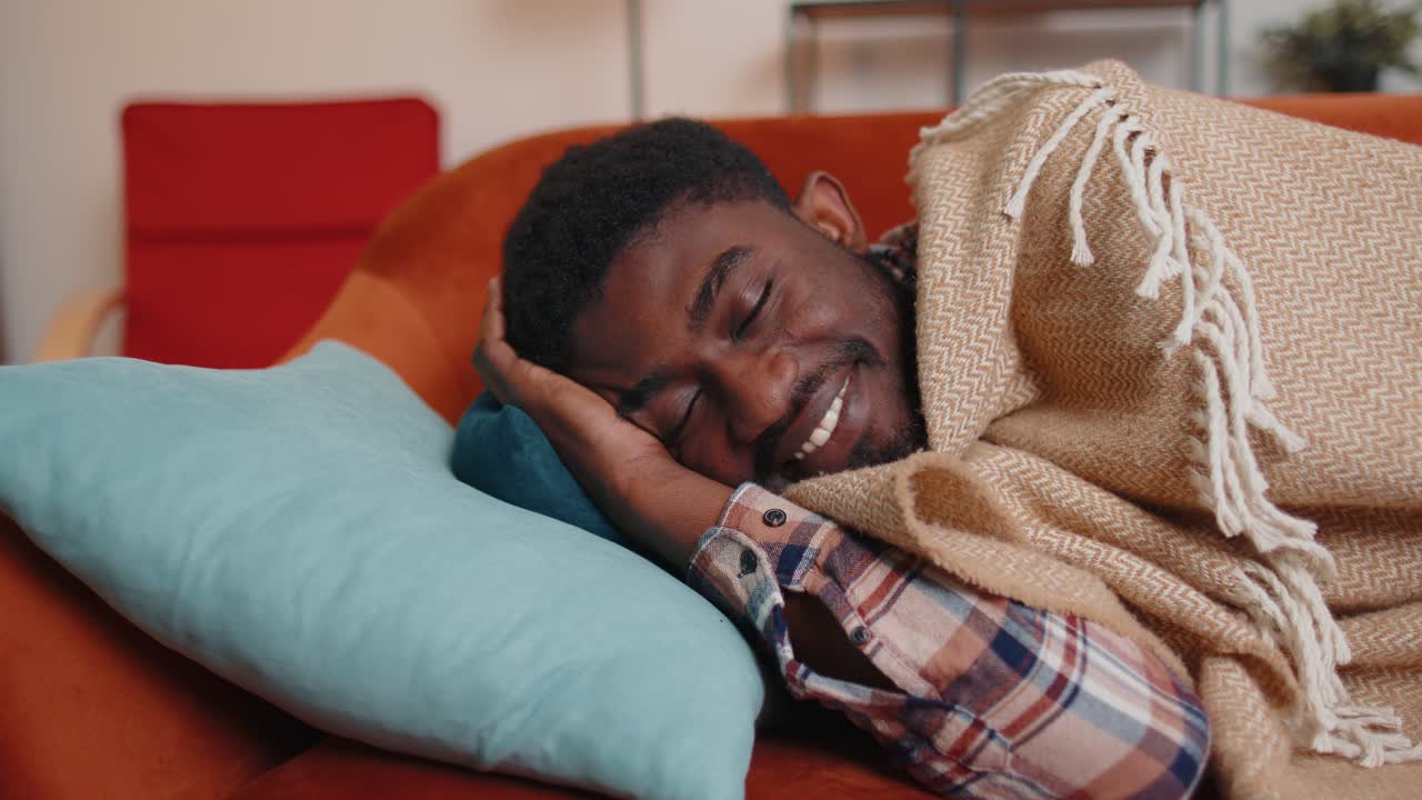 African american young man sleeping quietly in bedroom at home smiling lying on comfortable bed
