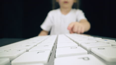 girl-plays-with-computer-keyboard-pressing-different-keys