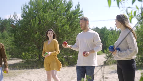 side view of caucasian young man throwing a petanque ball on the beach on a sunny day