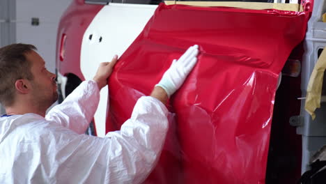 la aplicación de envoltura de vinilo rojo a una puerta de coche