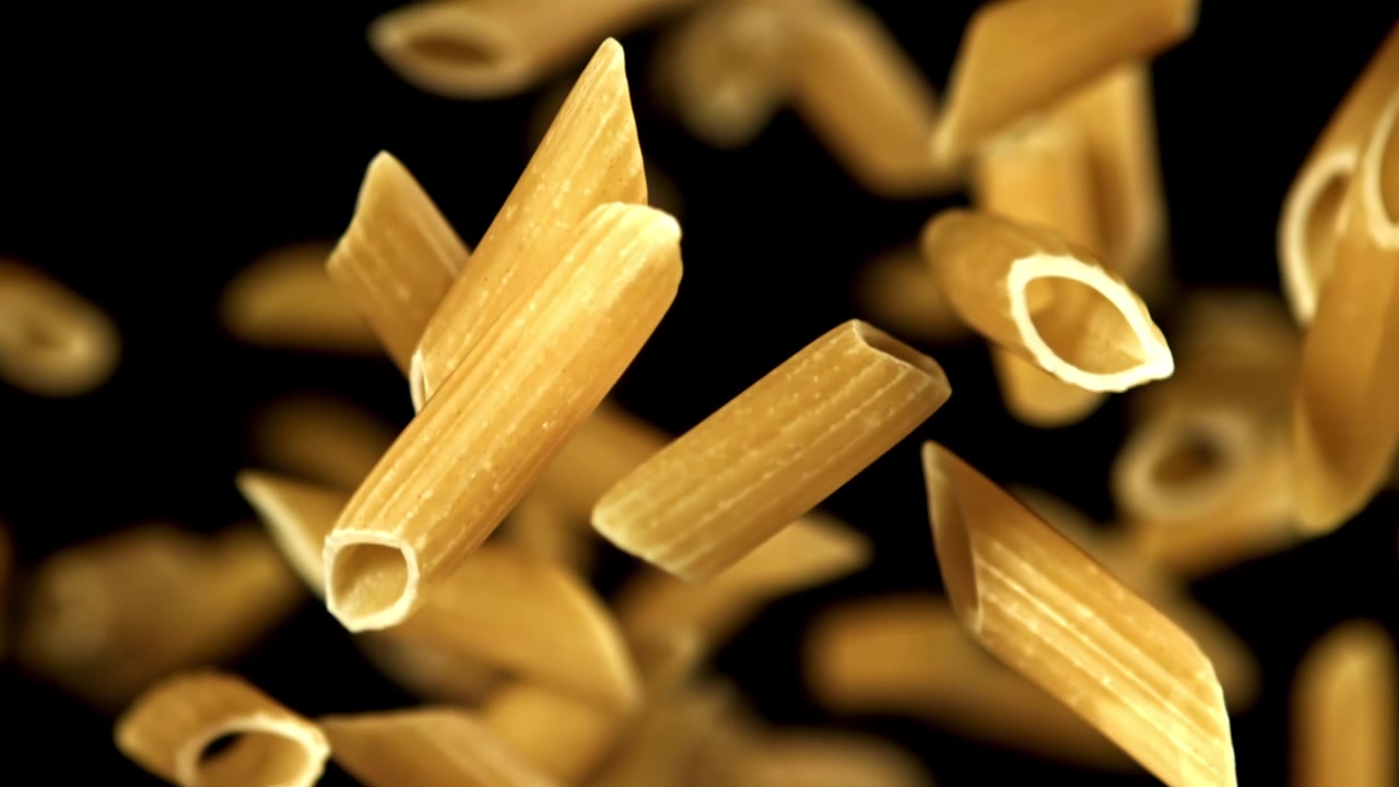 Penne secche che cadono al rallentatore su sfondo nero