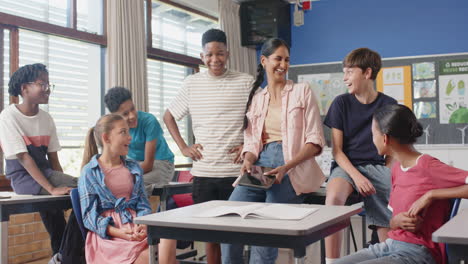 in school, teacher using tablet and interacting with students in classroom