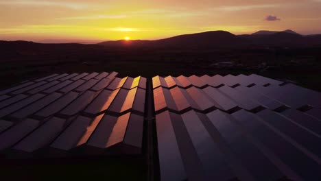Establisher-aerial-view-of-large-solar-panel-power-station-at-sunset