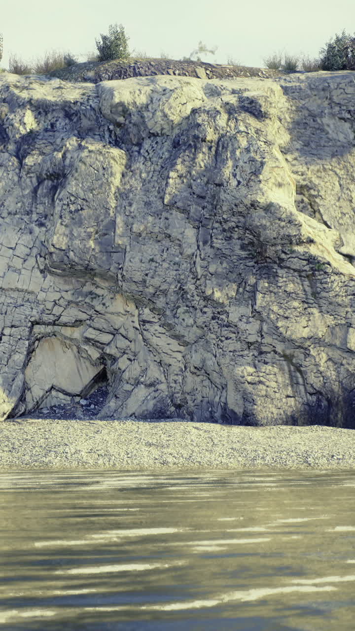 Natural rock formation along a serene riverbank with calm water reflections