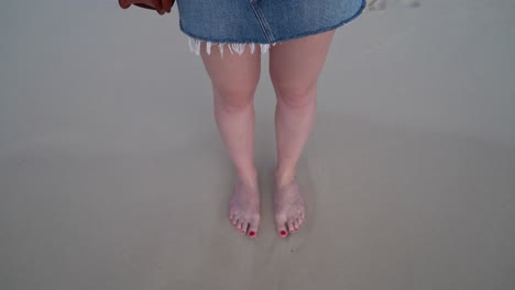 waves splashing on white woman's feet on a tropical island